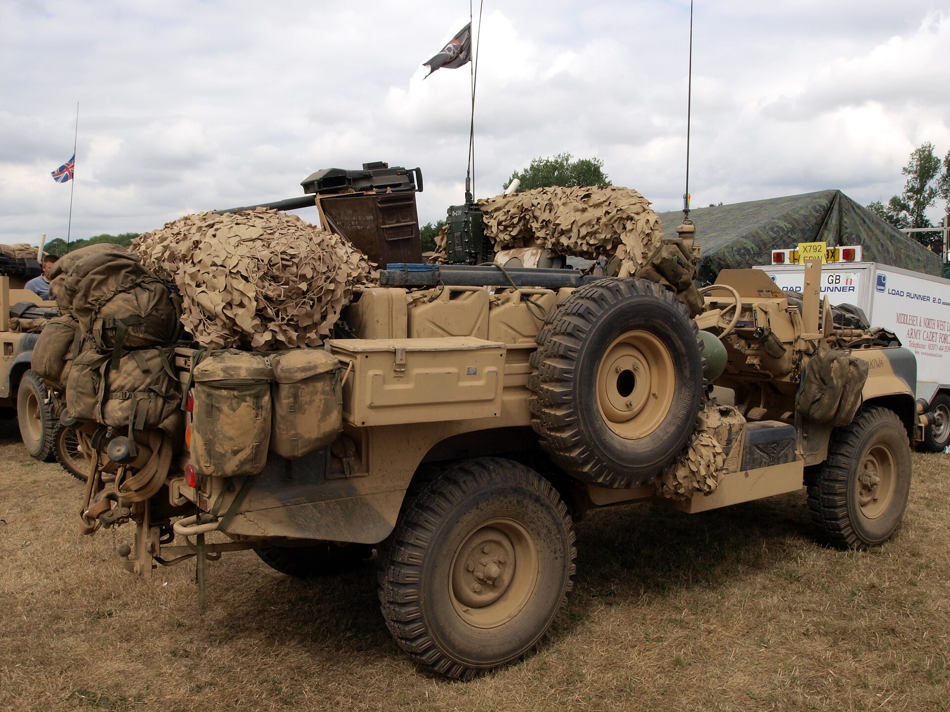 Preserved SAS Land Rover 110 Desert Patrol Vehicle in desert sand, laden with jerrycans and camouflage netting